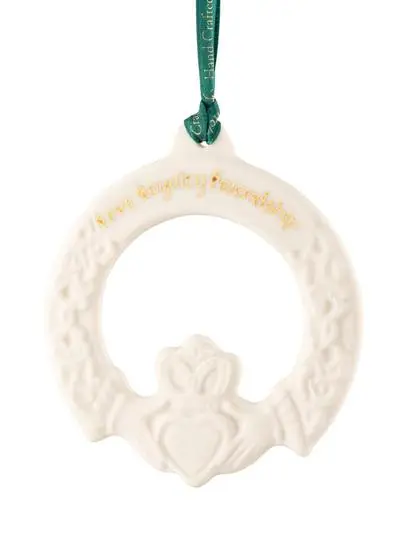 Claddagh Friendship Ornament with inscription love, loyalty and friendship in gold hanging from a green ribbon isolated on a white background